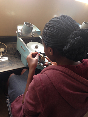A student at Tanzania’s Arusha Gemmological & Jewelry Vocational Training Centre practices cutting techniques on a marble.