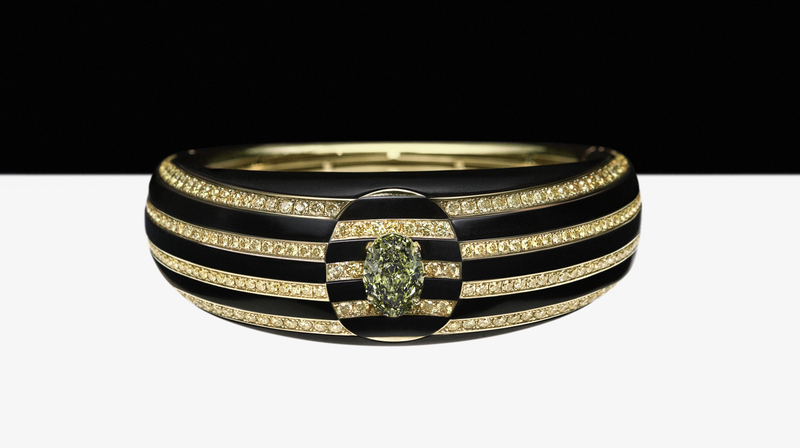 A 3.02 carat fancy oval-shaped deep greyish-green diamond is set in a concave indentation inside the bracelet 