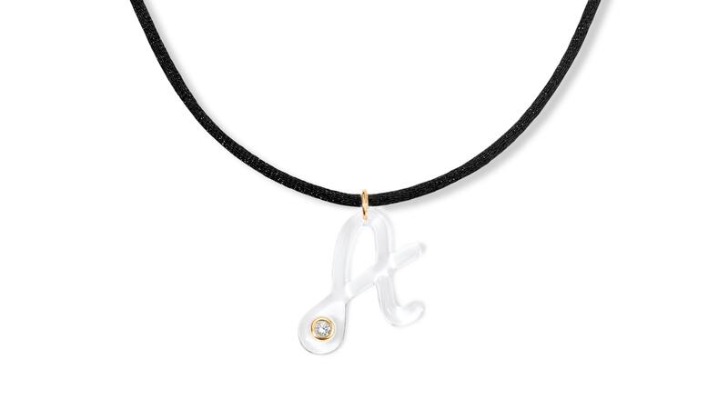 A letter necklace showcasing a “Claire” resin “A” with a 0.13-carat lab-grown diamond set in 14-karat yellow gold and strung on a black silk chord ($595) Alison Lou Lumière Letter Cord Necklace