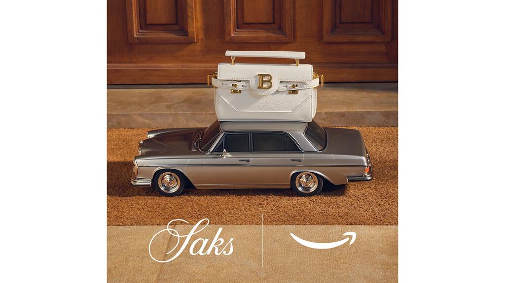 The “Saks Arrives on Amazon” editorial campaign takes a playful approach to delivering luxury goods to customers’ front doors. Balmain handbag on top of vintage car