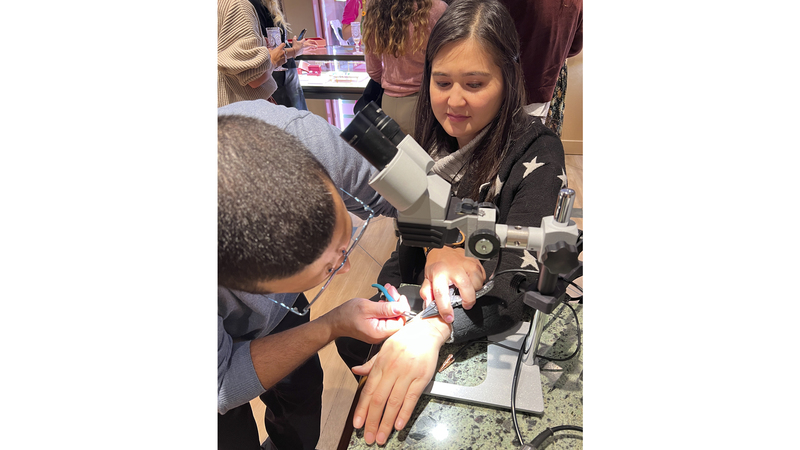 Bench jeweler Ramon Andino uses Gesswein’s PUK 6 Welder with SM6 Microscope and Flow Regulator to affix the bracelets to the wrist of each attendee, as seen here.