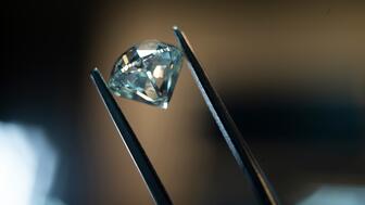 De Beers polished diamond in tweezers 