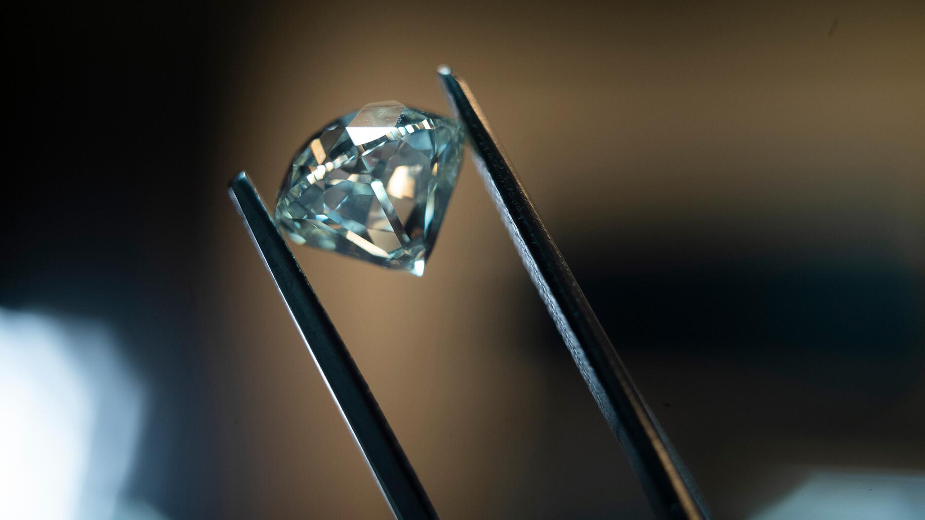 De Beers polished diamond in tweezers 